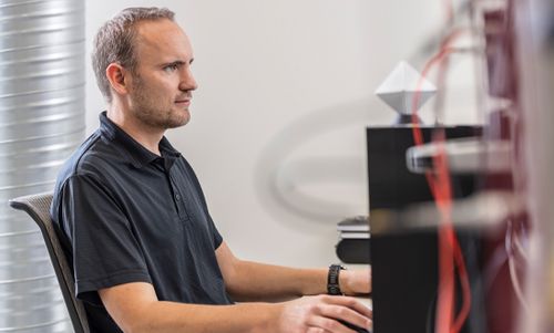 Mitarbeiter der FSM AG arbeitet konzentriert an einem Computer in einer technischen Umgebung.