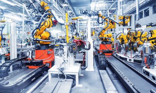 Automatisierte Produktionshalle mit zahlreichen Industrierobotern, die an Förderbändern arbeiten.