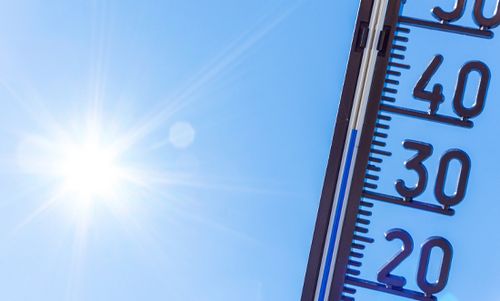 Thermometer, das Temperaturen über 30 Grad Celsius anzeigt, vor einem sonnigen, blauen Himmel.